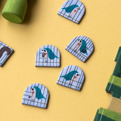 Kleine Pappmarker mit gezeichneten Vögeln in Käfigen.