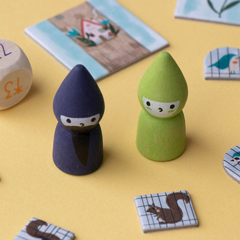 Zwei Spielfiguren aus Holz – ein Zauberer in Dunkelblau und eine Fee in Grün – auf gelbem Hintergrund.