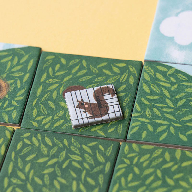 Spielkarte mit grünem Blätterhintergrund und einem im Käfig sitzenden Eichhörnchen.