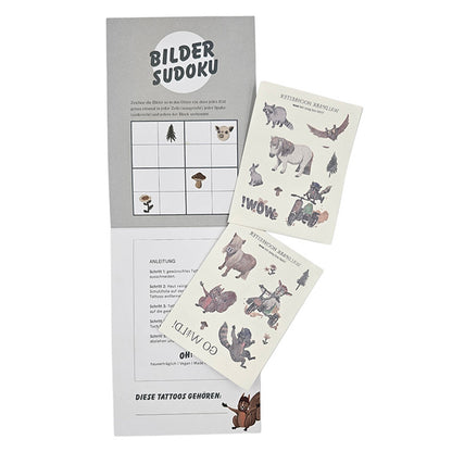 Zwei Bögen mit Waldpark Hochreiter-Tattoos liegen auf einer geöffneten grauen Mappe mit einem Bilder-Sudoku-Spiel.