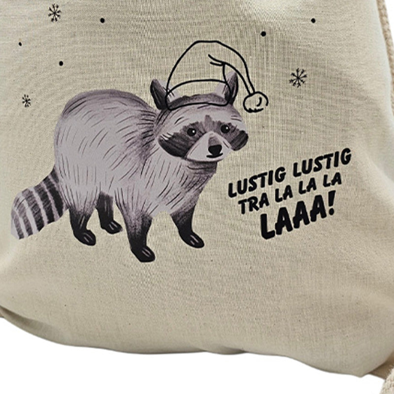 Nahaufnahme des Druckmotivs auf dem Stoffbeutel: Ein Waschbär mit Weihnachtsmütze, Schneeflocken und der Aufschrift „Lustig lustig tra la la la laaa!“.