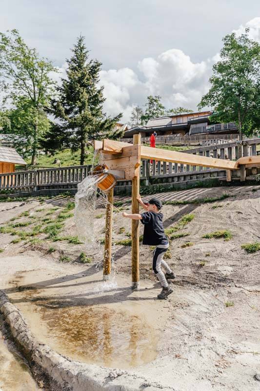 Wasserspielplatz Junge mit Kübel - Waldpark Hochreiter