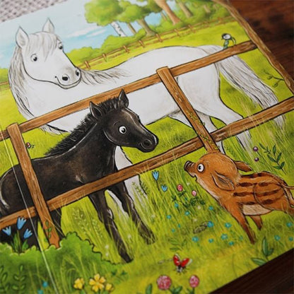 Illustration mit einem weißen Pferd und einem schwarzen Fohlen auf einer Wiese hinter einem Holzzaun; davor steht ein neugieriger Frischling zwischen bunten Blumen.