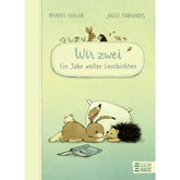 Buchcover von „Wir zwei – Ein Jahr voller Geschichten“ von Michael Engler und Joëlle Tourlonias. Ein Hase und ein Igel liegen gemütlich vor einem Kissen auf dem Bauch und schauen gemeinsam auf ein geöffnetes Buch.