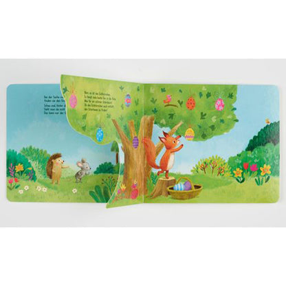 Buchseite: Klappseite geöffnet – das Eichhörnchen kommt hinter dem Baum hervor und hängt bunte Ostereier an die Äste.