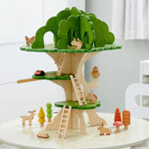 Holzspielzeug-Baum mit Tieren und Bäumen, darunter Reh, Marienkäfer, Hase und bunte Pilze auf einem Tisch platziert.