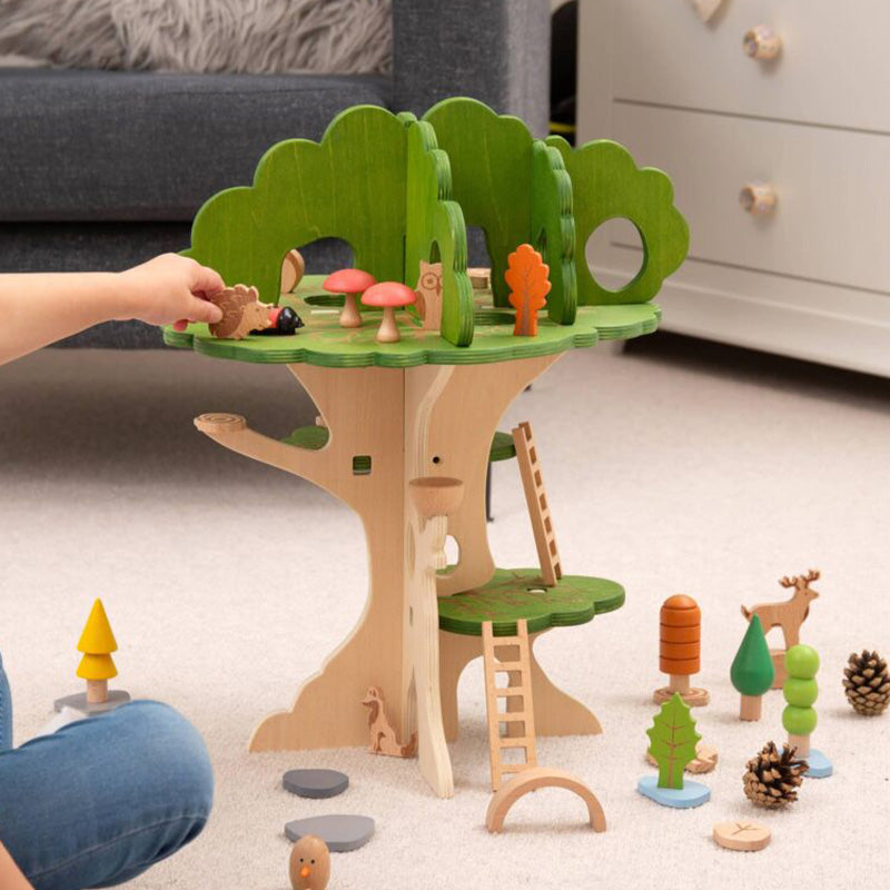 Holzspiel-Baum mit bunten Pilzen, Tieren und Figuren; eine Hand platziert eine Figur auf der oberen Plattform.