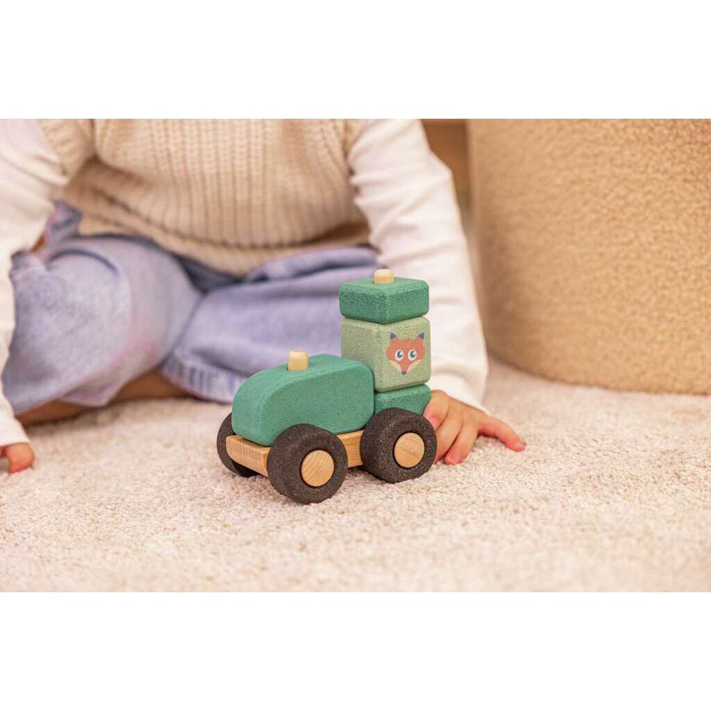 Kind spielt mit Kork Traktor am Boden