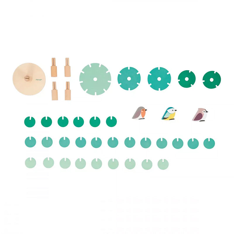 Alle Einzelteile des Holzspielzeugs: Holzscheiben in verschiedenen Grüntönen, Bauteile für den Baum und drei kleine Holzvögel.
