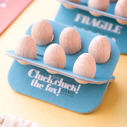 Nahaufnahme einer blauen Eierablage mit Holzeiern und der Aufschrift „Cluck, cluck! the fox!“.