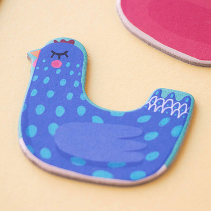 Detailansicht einer blauen Hühnerfigur aus Karton mit Punkten und geschlossenen Augen.