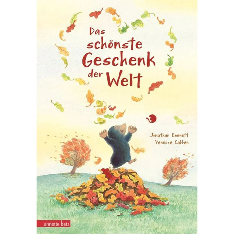 Buchcover ‘Das schönste Geschenk der Welt’, Illustration eines Maulwurfs, der jubelnd Blätter in die Luft wirft, mit einem großen Laubhaufen im Vordergrund.