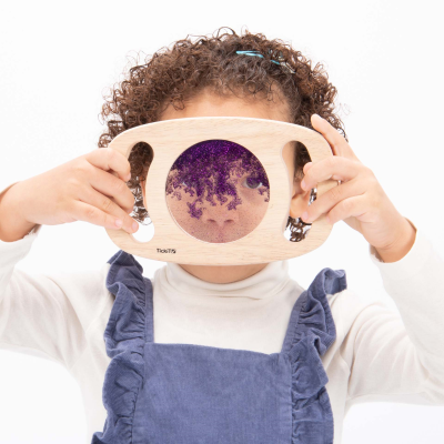 Kind schaut durch lila Easy Hold Glitzertafel