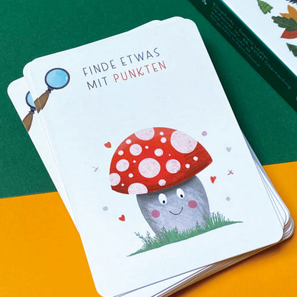 Detailaufnahme eines Kartenstapels mit Suchkarte Pilz mit Punkten, fröhliche Illustration auf weißer Karte vor grün gelbem Hintergrund