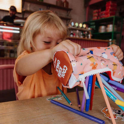 Kind schüttelt alle Stifte aus der Federmappe in der Farbe Flore