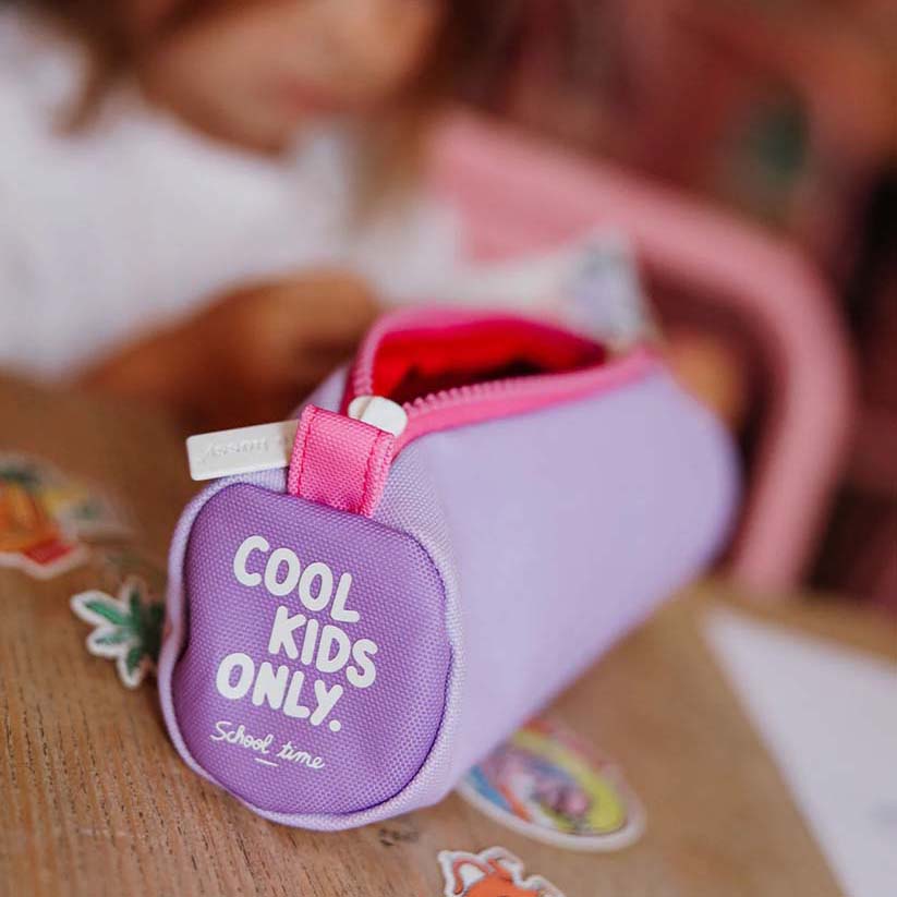 geöffnete Federmappe in der Farbe Mini Mauve liegt am Tisch, Kind ist im Hintergrund zu sehen