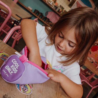 Kind sitz am Tisch und schaut neugierig in Federmappe in der Farbe Mini Mauve