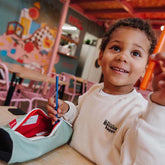 Kind hält Stift in die Kamera während Federmappe in der Farbe Mini Pistache am Tisch liegt