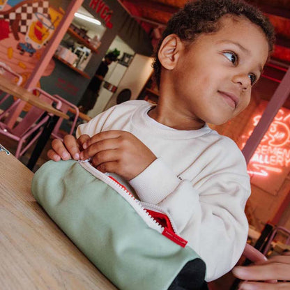 Kind sitzt mit Federmappe in der Farbe Mini Pistache am Tisch und schaut nach rechts