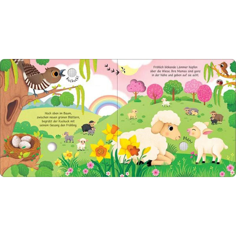 Buchseite mit frühlingshafter Wiesenlandschaft, blühenden Blumen, Lämmern, Schafen, einem Kuckuck im Baum, Regenbogen und mehreren Tieren in sanfter, kindgerechter Illustration