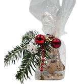 Nahaufnahme eines Geschenksets im Zellophan, dekoriert mit Tannenzweig, roten Kugeln und Holzanhänger in Glockenform