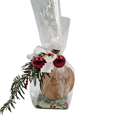 Geschenkset im Zellophan mit Holzanhänger ‚ein braves Christkindl‘, dekoriert mit roten Kugeln und Tannenzweig.