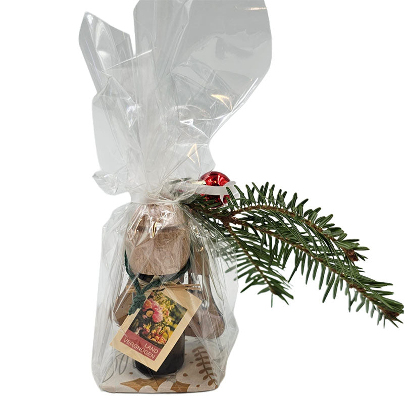 Geschenkset mit Holzduftflasche ‚Landvergnügen‘ und Tannenzweig, verpackt in Zellophan.