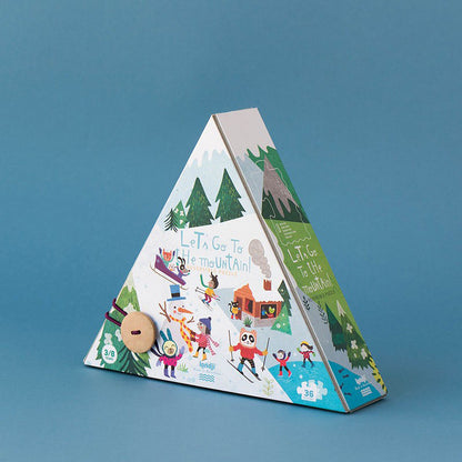 Rückseite der Pyramidenverpackung des Puzzles mit winterlicher Illustration: Kinder beim Skifahren, Rodeln und Schneemannbauen, beschriftet mit „Let’s Go to the Mountain!“.