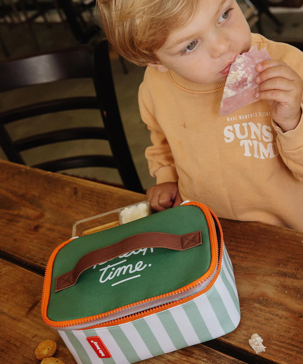 kind beisst in Jausenbrot aus lunchtasche mit grünen streifen