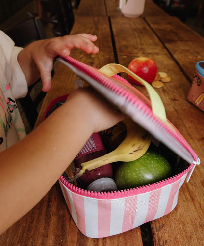 kind nimmt banane aus lunchtasche mit rosa streifen