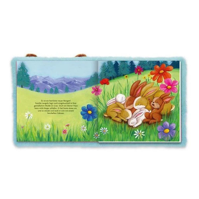 Hasenfamilie liegt gemeinsam auf einer Blumenwiese vor Berglandschaft