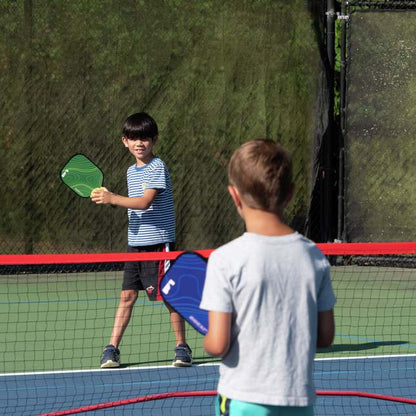 Zwei Kinder spielen mit dem Pickleball auf dem Tennisplatz