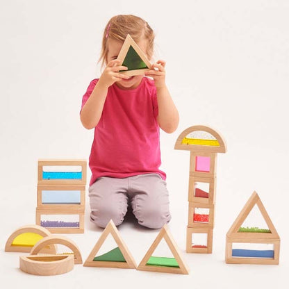 mädchen sitzt hinter sensorischen bausteinen und schaut durch einen grünen Baustein hindurch