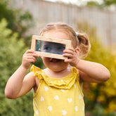 Mädchen mit baustein mit durscheinender Folie schaut durch die blaue Folie durch