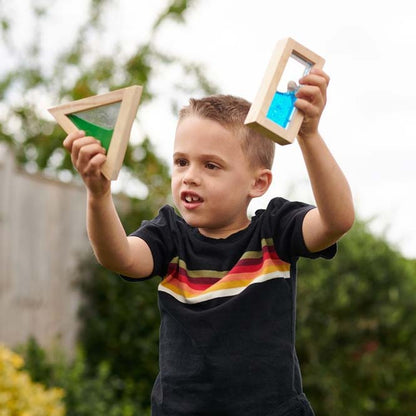Bub spielt im Garten mit zwei Bausteinen in der Hand