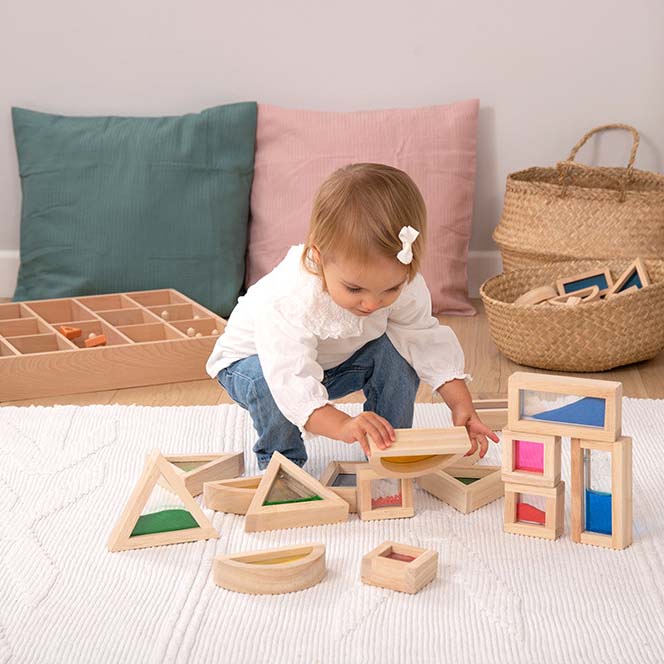 Kleinkind hockt am Boden und schaut sich sensorische Bausteine an