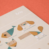 Nahaufnahme der Anleitung des Spiels mit Tieren aus Holzformen, darunter ein Hund und ein Fisch, mit dem Londji-Schriftzug oben.