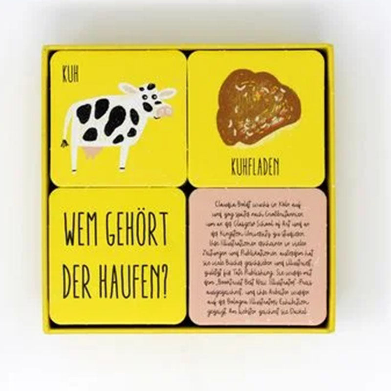 Spielkarten mit gelbem Hintergrund: Eine Karte zeigt eine Kuh, die zweite einen Kuhfladen, die dritte den Titel „Wem gehört der Haufen?“ und die vierte enthält Text.