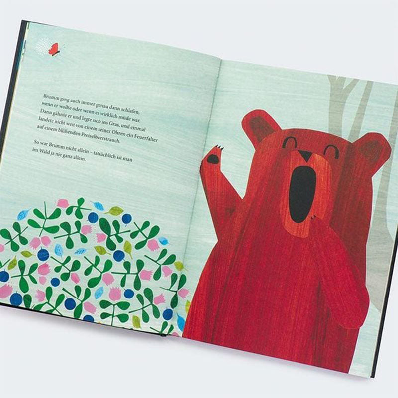 Buchseite – Bär gähnt neben Blumen.