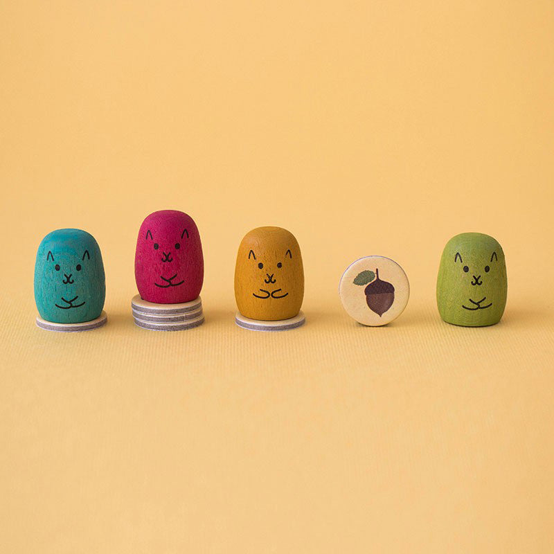 Spielfiguren in allen vier Farben mit gesammelten Spielchips in Form von Eicheln.