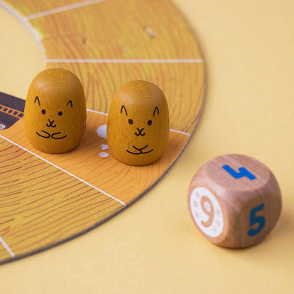 Zwei gelbe Eichhörnchen-Spielfiguren neben einem Würfel.