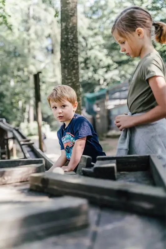 Waldkugelbahn - zwei Kinder im Wald an einer Stationen der Kugelbahn mit Schleusen. Sie beobachten gespannt.