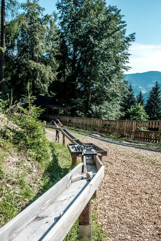 Waldkugelbahn Steiermark - zwei Kinder laufen weiter entfernt, sie haben die Station mit den vielen Hinternissen schon hinter sich gelassen